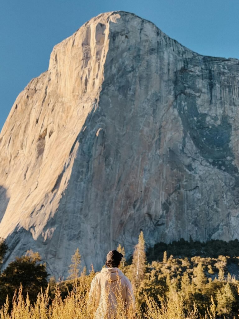 Man admiring the towering El Capitan in Yosemite under clear skies.