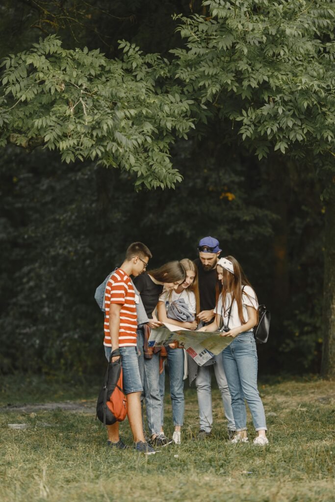 Group of teenagers looking at a map in a forest, planning an adventure trip.