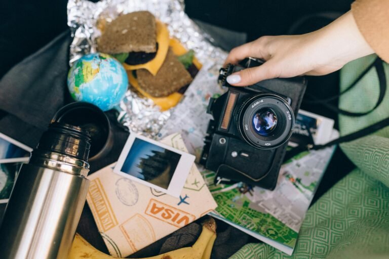 Capture memories with a vintage camera amid travel essentials like a map, snacks, and polaroid photos.
